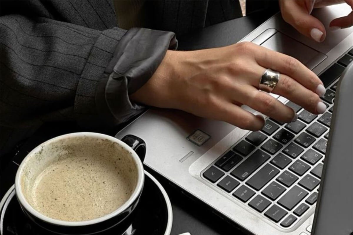 mulher mexendo em notebook tomando cafe